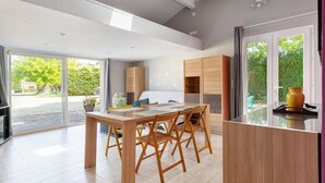 A modern kitchen with a wooden table and chairs, a built-in oven, and a large window.
