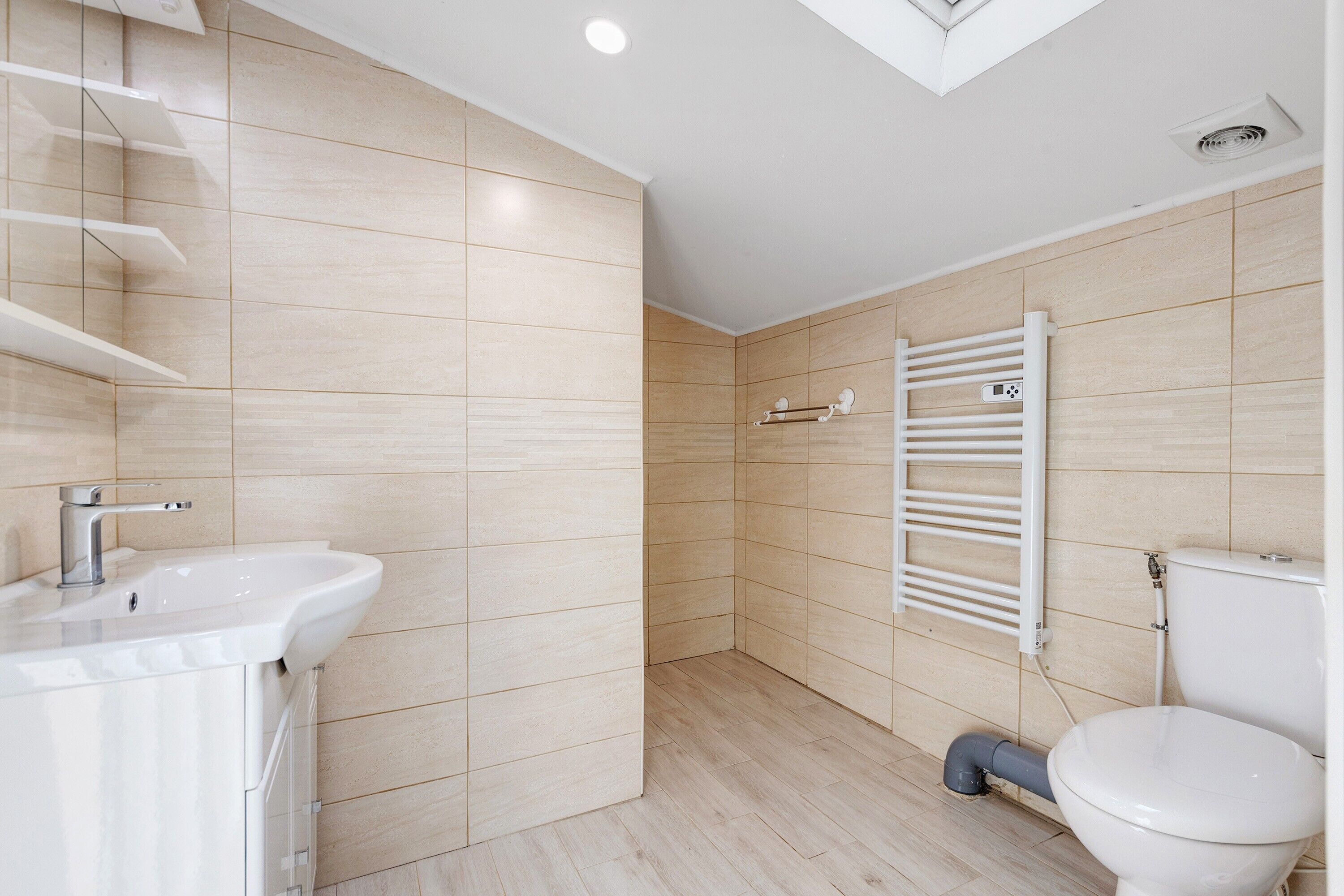 Une salle de bain moderne avec un lavabo, des toilettes et un porte-serviettes, le tout de couleur blanche.