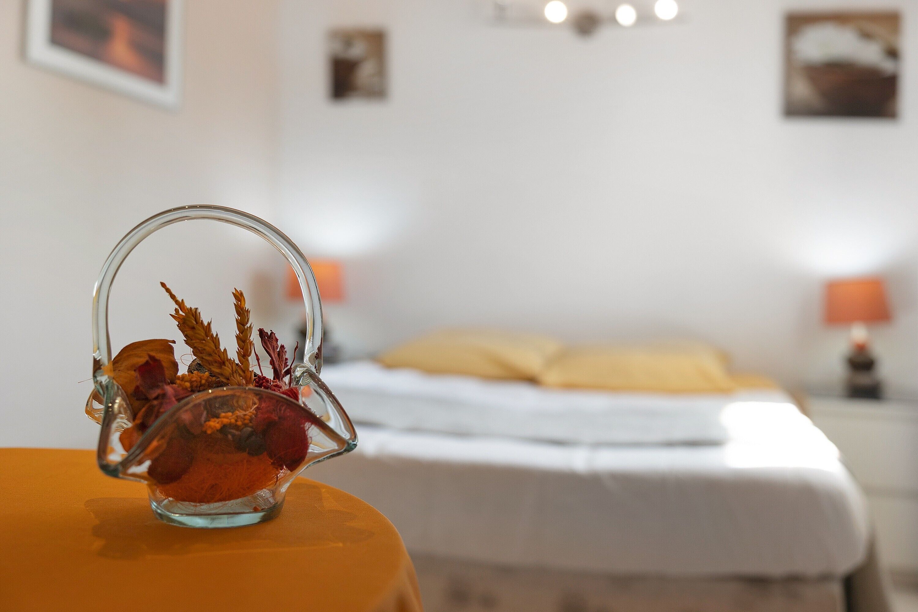 Una habitación con una cama, una mesita de noche con una lámpara y un cuenco de vidrio decorativo sobre una mesa.