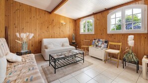 A wooden-paneled room with a bed, a sofa, a coffee table, a desk, and a chair. - Bed and Breakfast 'Chambre D'hôtes Capucine' with Shared Pool, Shared Terrace and Wi-Fi (Bégadan)