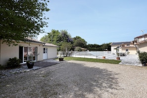 A courtyard with a gravel path, potted plants, and a building with a tiled roof. - Bed and Breakfast 'Chambre D'hôtes Capucine' with Shared Pool, Shared Terrace and Wi-Fi (Bégadan)