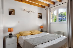 A bedroom with a bed, two bedside tables with lamps, a radiator, and a window with curtains. - Bed and Breakfast 'Chambre D'hôtes Capucine' with Shared Pool, Shared Terrace and Wi-Fi (Bégadan)