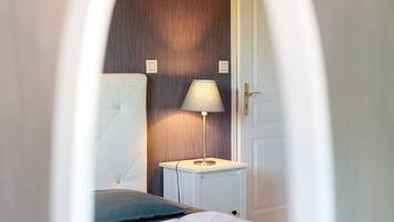 A bedroom with a bed, a bedside table with a lamp, and a door.