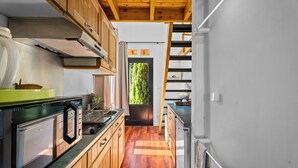 Eine kleine Küche mit Holzschränken, einem Edelstahlkühlschrank und Holzboden.