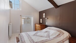 Un dormitorio con cama, cómoda, radiador, ventana y puerta.