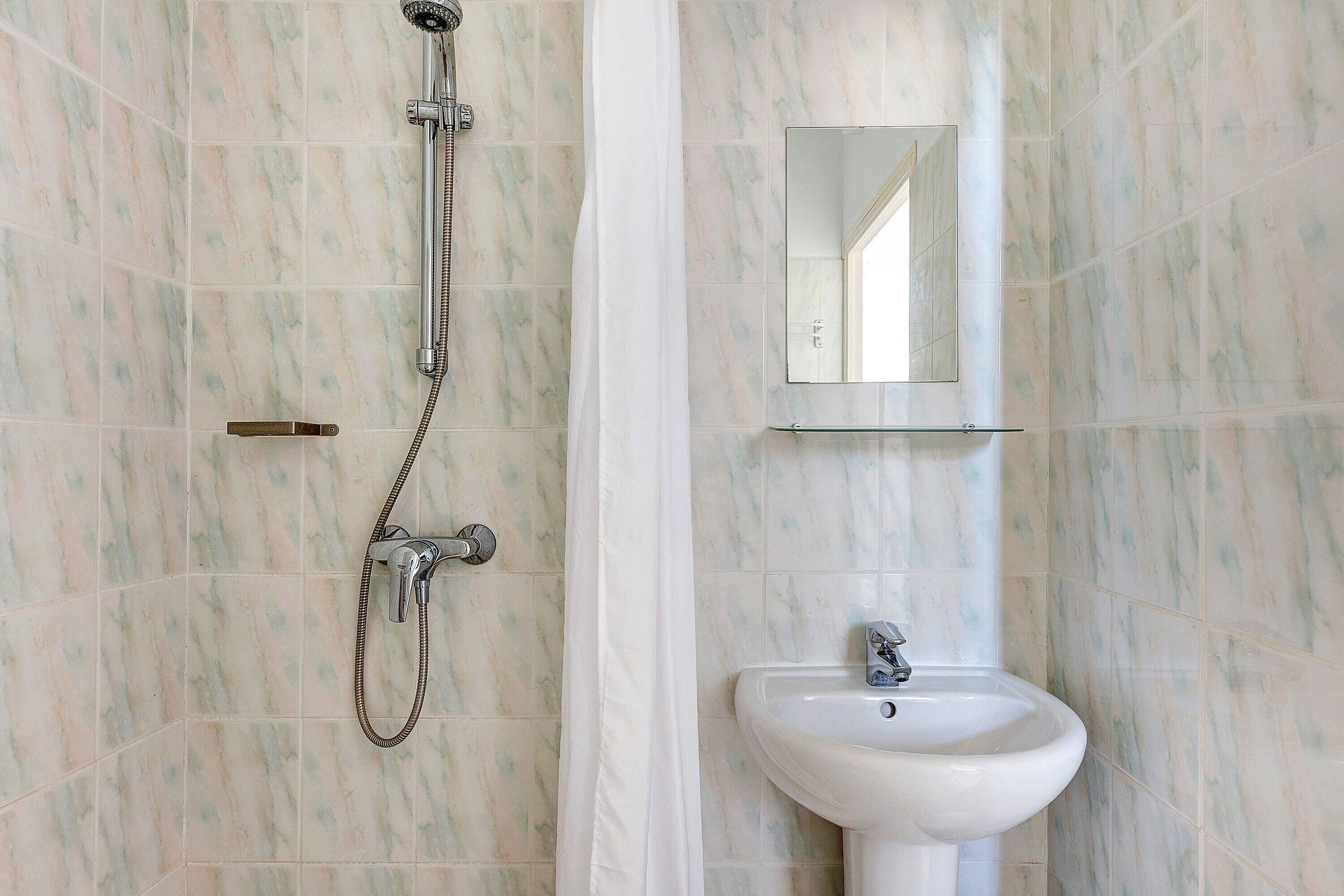 A bathroom with a shower, a sink, and a mirror.