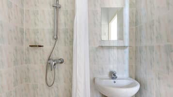 A bathroom with a shower, a sink, and a mirror.
