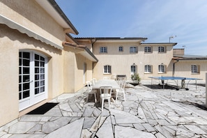 A patio with stone flooring, a table with chairs, and a ping pong table.