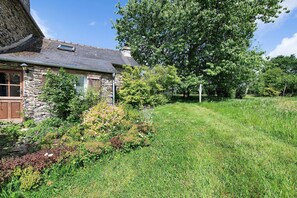 Une maison en pierre avec un toit en pente, une porte en bois et une petite fenêtre.