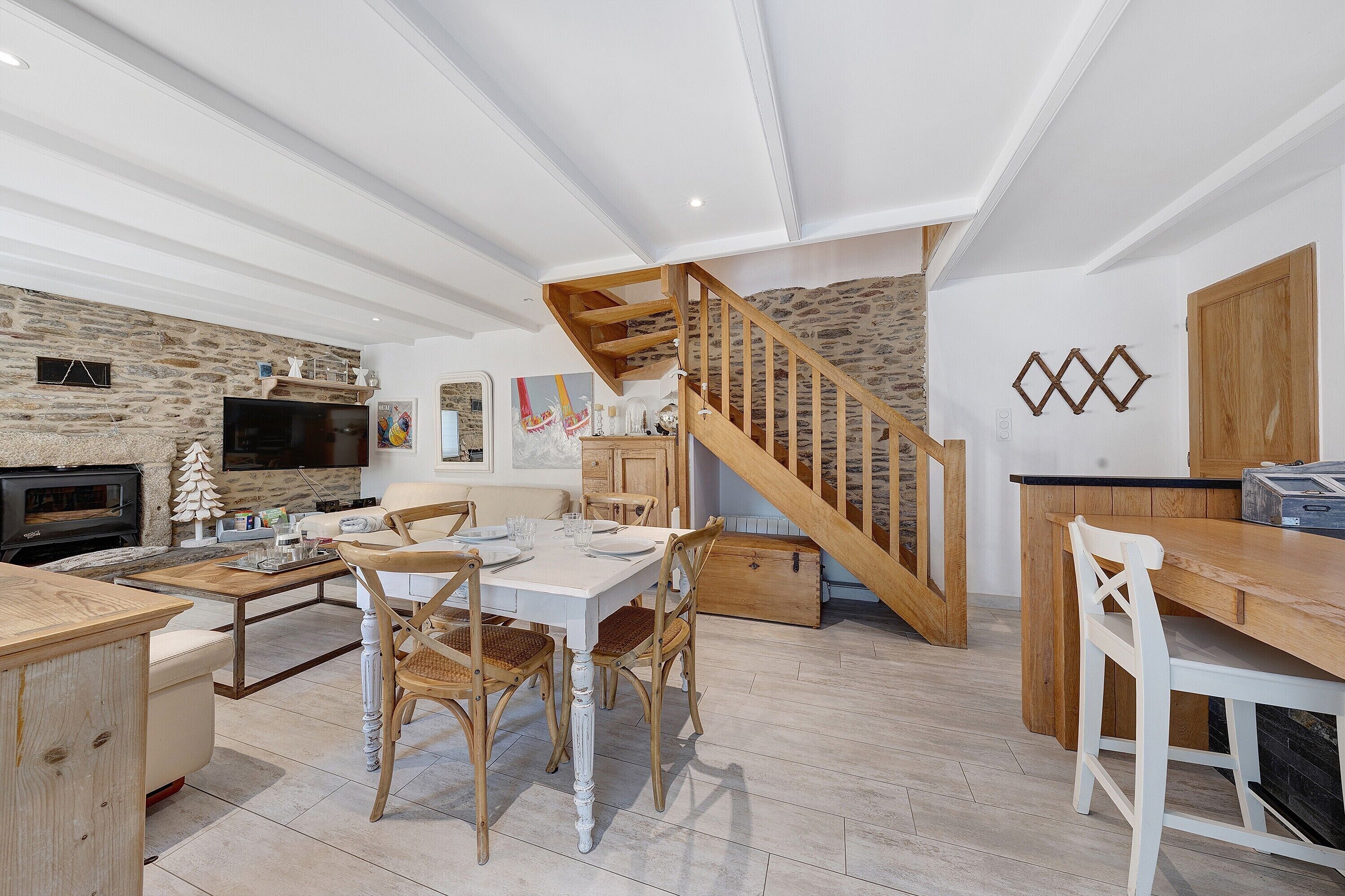 Ein modernes Wohnzimmer mit Kamin, Esstisch aus Holz und einer Treppe.