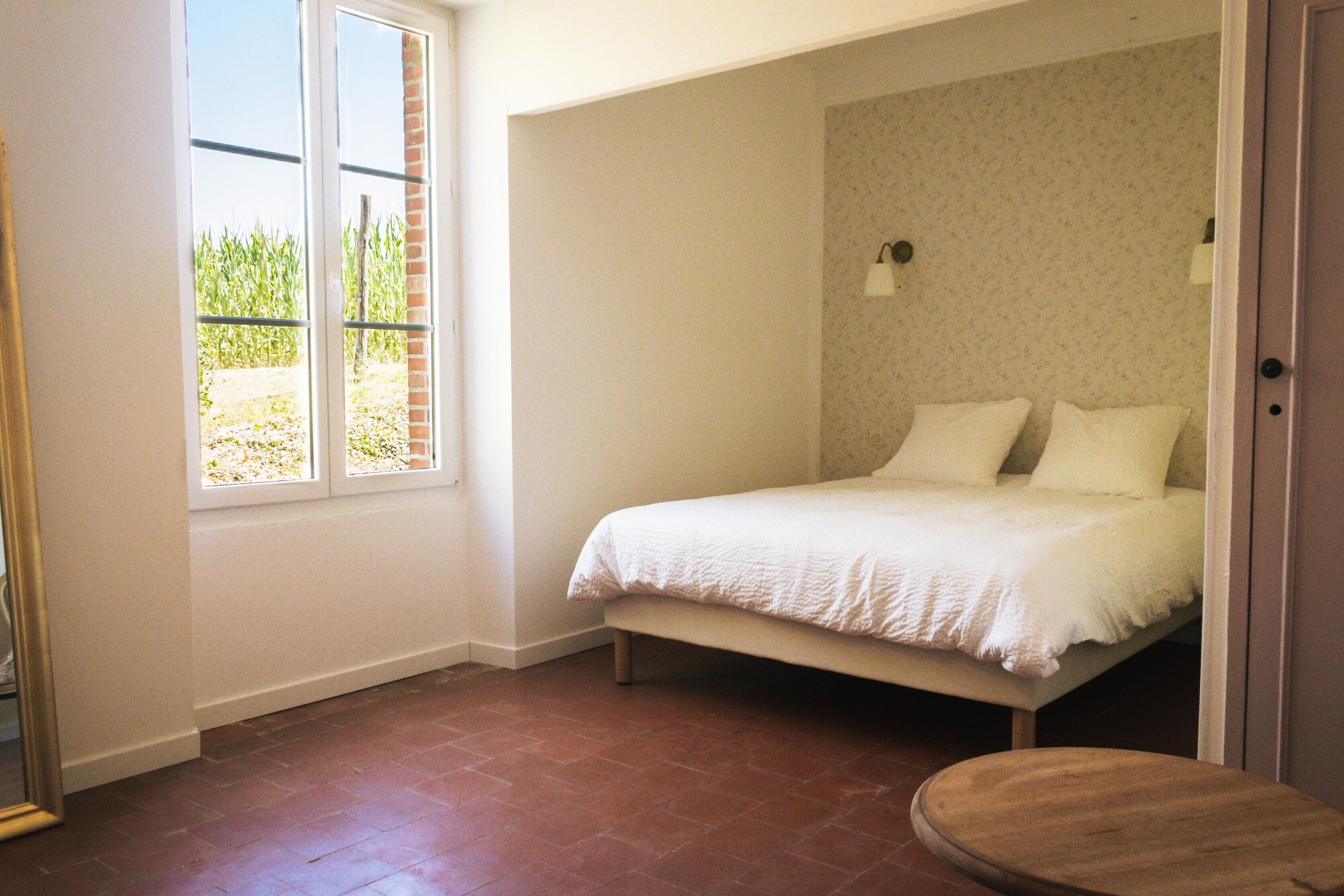 A bedroom with a bed, a window, and a door.
