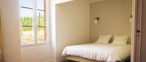 A bedroom with a bed, a window, and a door.