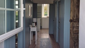 A hallway with a table, chairs, and a hanging light fixture.