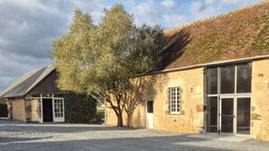 A building with a gravel driveway, a tree, and a stone wall.
