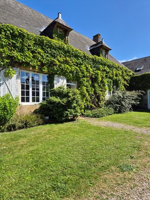 Ett hus med en trädgård, ett fönster och en skorsten.