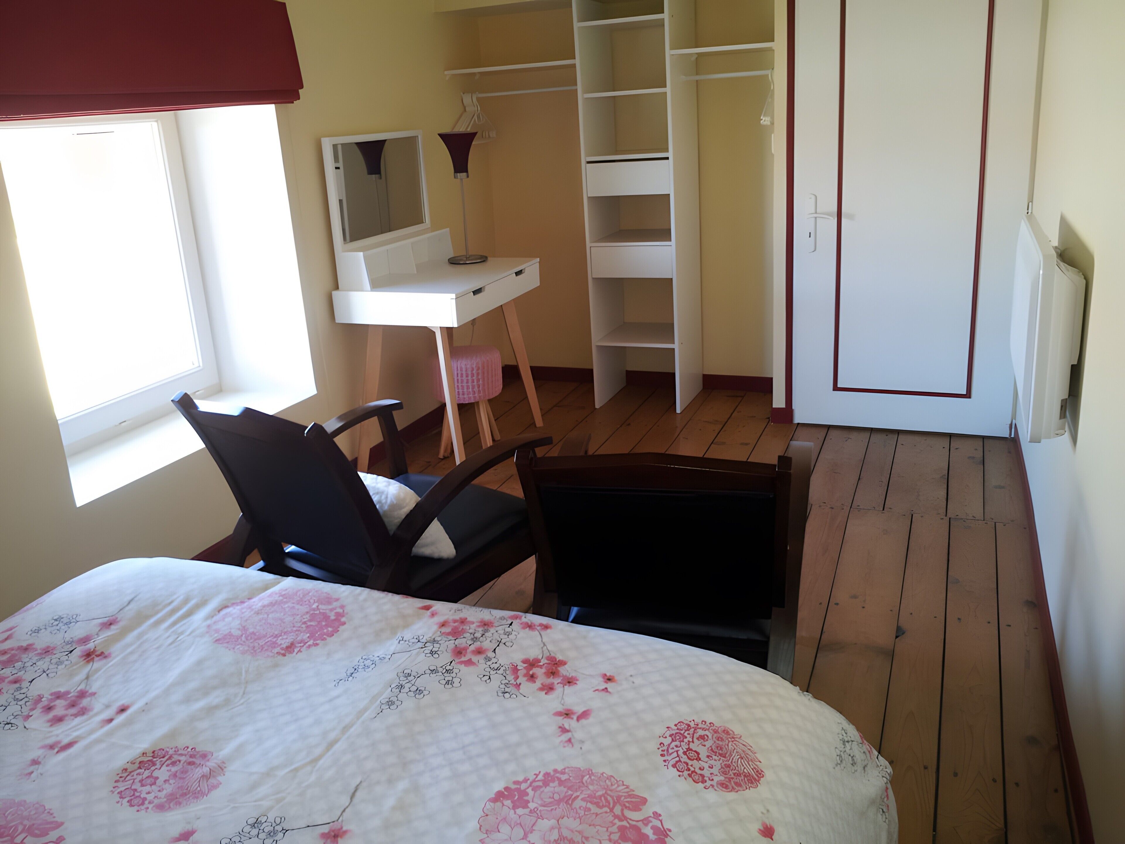A bedroom with a bed, a desk, a chair, a wardrobe, and a mirror.