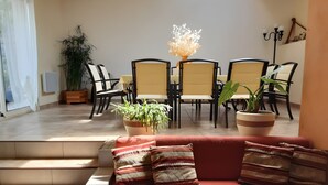 En moderne stue med sofa, stole og krukker med planter.