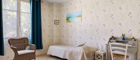 Une chambre à coucher avec un lit, une chaise, un bureau et une fenêtre avec des rideaux.