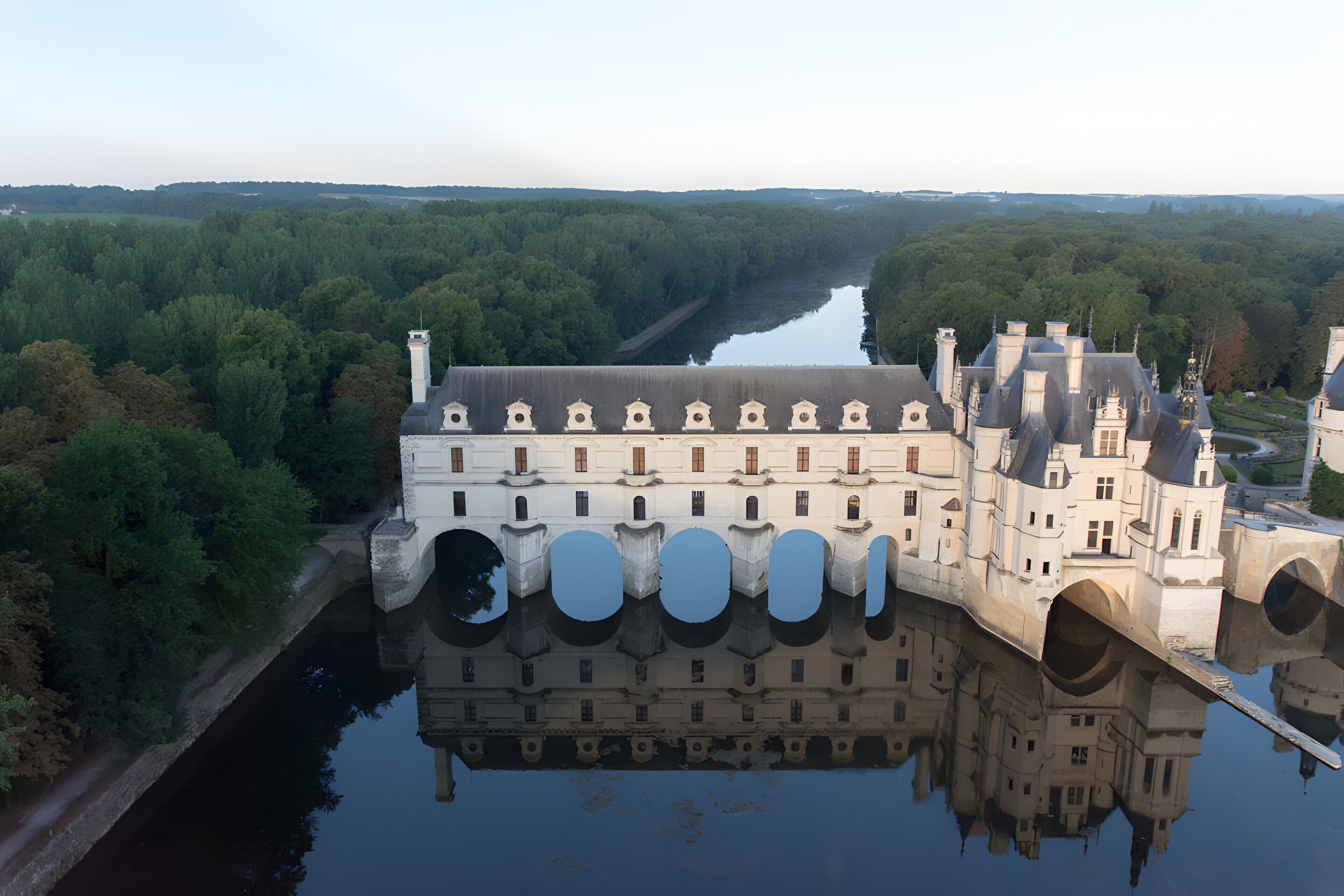 Ein großes, historisches Gebäude mit zahlreichen Bögen und Spiegelung im Wasser.