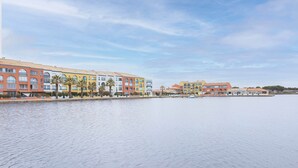 A waterfront hotel with multiple buildings, a paved walkway, and palm trees. - Maison Goéland – A Relaxing Getaway Between Land and Sea, Shared Pool & Balcony (Le Barcarès)