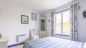 Una camera da letto con un letto, un armadio, un termosifone e una finestra con tende.