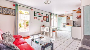 Un soggiorno moderno con un tavolino in vetro, un divano rosso e una cucina sullo sfondo.