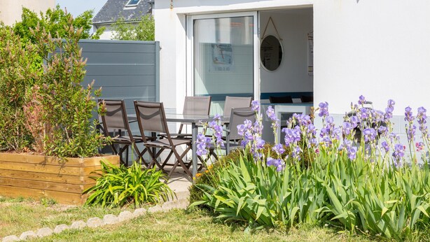 A house with a patio, outdoor seating, and purple flowers. - Holiday Home 'L'escale bleue' with Shared Terrace, Private Garden & Wi-Fi (Plomeur)