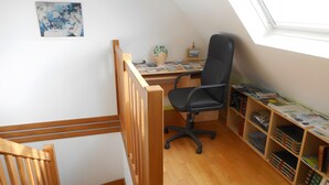 Une pièce comprenant un bureau, une chaise, une bibliothèque et une fenêtre.