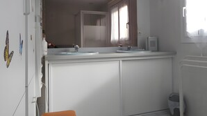 Une salle de bain avec un double lavabo, un miroir et une fenêtre.