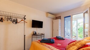 Une chambre à coucher avec un lit, une télévision, un étendoir et une fenêtre avec des stores.