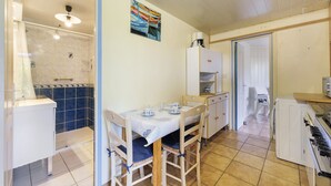 Une cuisine équipée d’une table à manger, de chaises, d’un lave-linge et d’un espace douche.