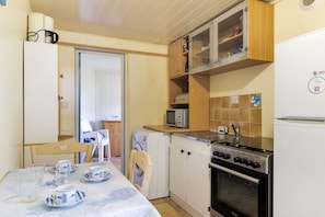 Una cocina compacta equipada con lavadora, microondas, estufa y refrigerador.