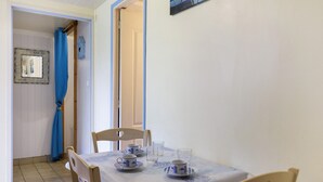 Un coin repas avec une table dressée pour quatre personnes, des chaises et un rideau bleu.