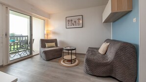 A modern living room with a sofa, armchair, round side table, and a framed picture on the wall. - Sailing, port, near beach & Thalasso, parking, towels & cleaning not included (Arzon)