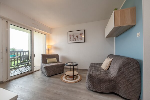 A modern living room with a sofa, armchair, round side table, and a framed picture on the wall. - Sailing, port, near beach & Thalasso, parking, towels & cleaning not included (Arzon)
