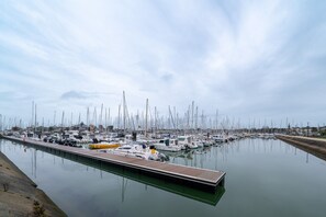 A marina with numerous boats docked along a calm waterway, a wooden pier, and a clear sky. - Le Sailing Apartment: Port View, Near Beach & Thalasso, Private Parking (Arzon)
