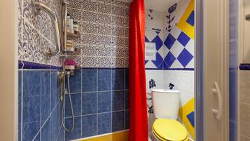 A bathroom with a shower, toilet, and a red curtain.