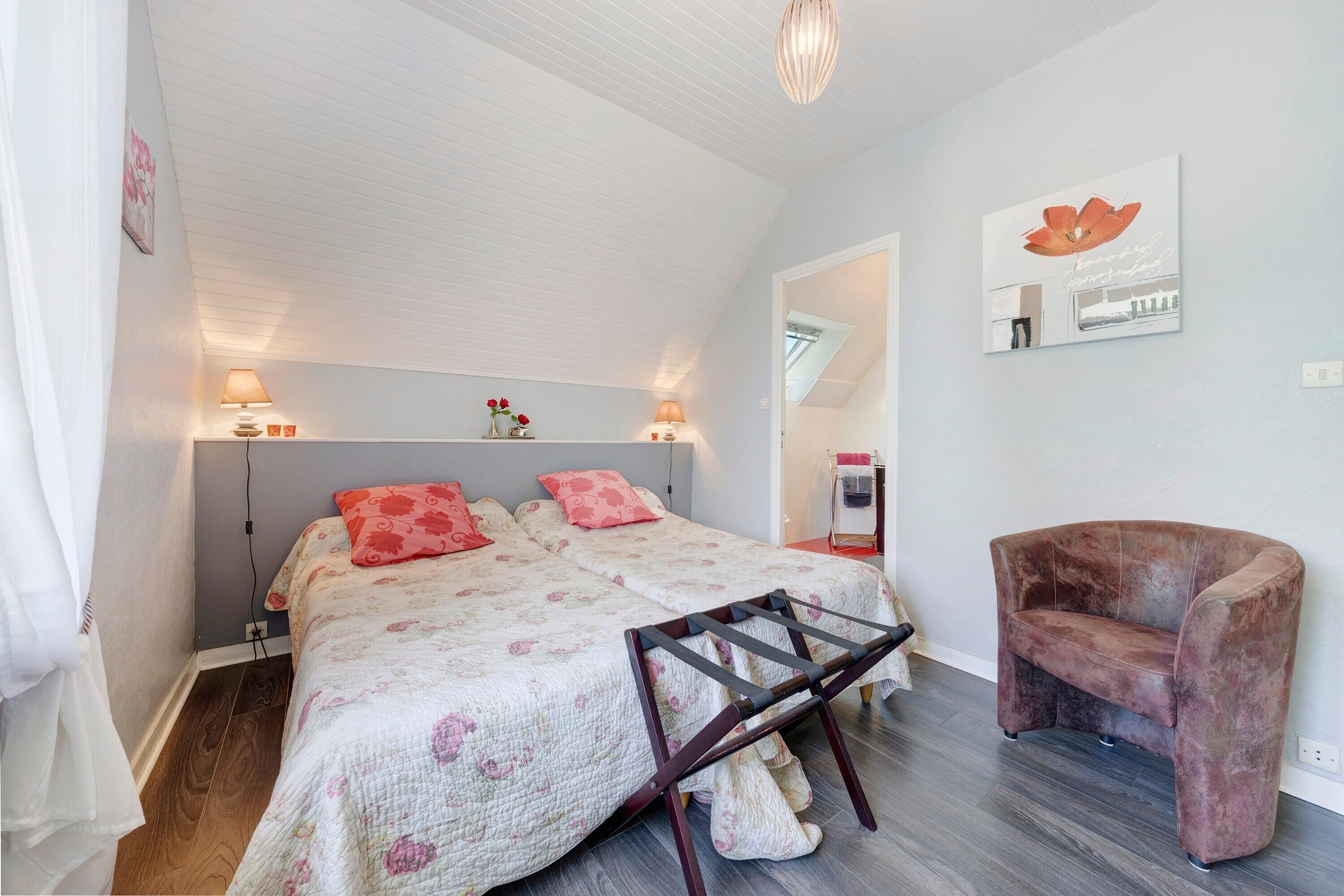 Une chambre avec deux lits, une chaise et un miroir au mur.