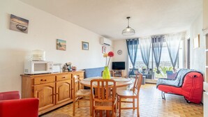 Un coin repas comprenant une table ronde, des chaises, un four à micro-ondes et un téléviseur.