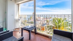 Un balcon donnant sur une marina, avec des meubles en osier et une table.