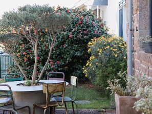 A garden with a table and chairs, surrounded by various plants and flowers. - Villa Roz, 2–6 Guests, 100 m from the Port, Perros-Guirec (Perros Guirec)
