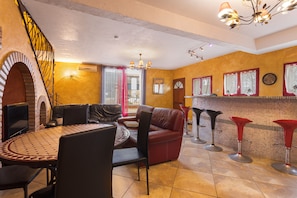 A cozy living area with a fireplace, a round coffee table, leather sofas, and a bar area with stools.