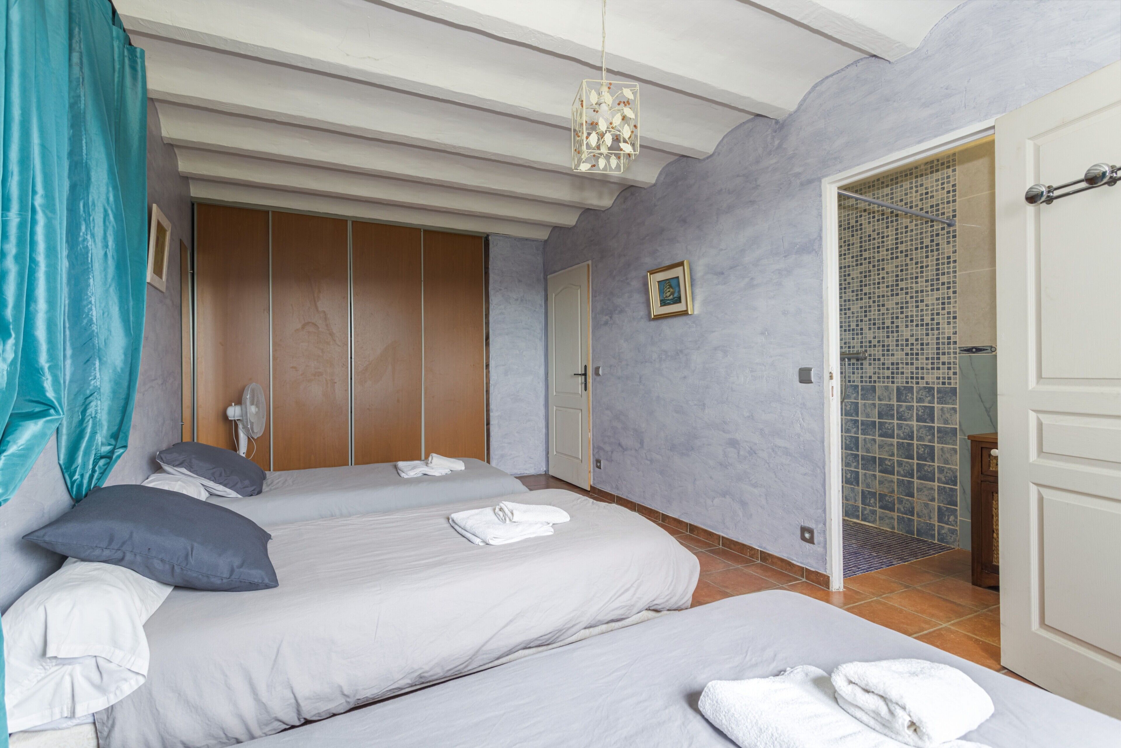 A hotel room with two beds, a shower area, and a door leading to a bathroom.