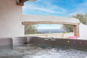 Un jacuzzi con vistas a un paisaje urbano, una pared de ladrillo y un cielo despejado.