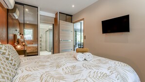A bedroom with a bed, a TV, and a sliding door leading to a bathroom.
