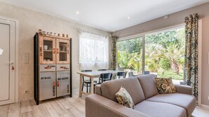A modern living room with a sofa, dining table, and a cabinet with glass doors.