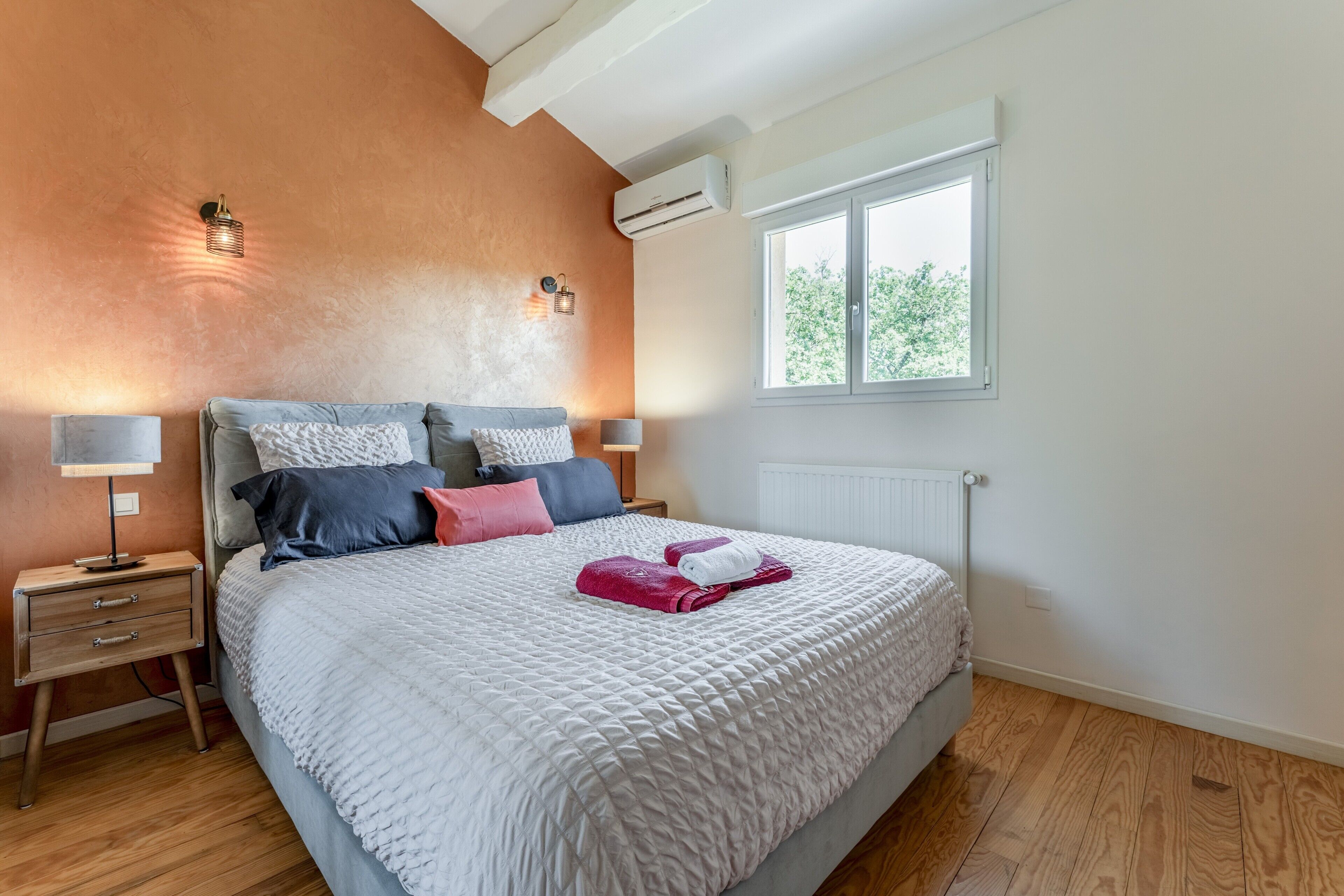 Une chambre à coucher avec un lit, des lampes de chevet, une fenêtre et un radiateur.