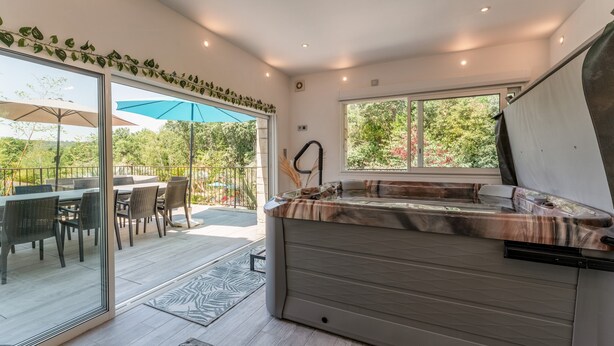 A modern kitchen with a built-in hot tub, large windows, and a patio area with outdoor furniture.