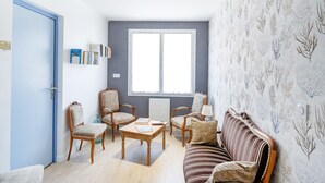 Une pièce avec une porte bleue, une grande fenêtre, un canapé à rayures et une bibliothèque.