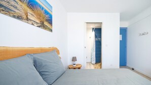 Une chambre à coucher comprenant un lit, une table de chevet, une lampe, un tableau et une porte donnant sur une autre pièce.